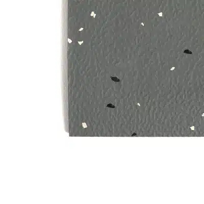 Close-up of dark gray textured paper with scattered white and black flecks.