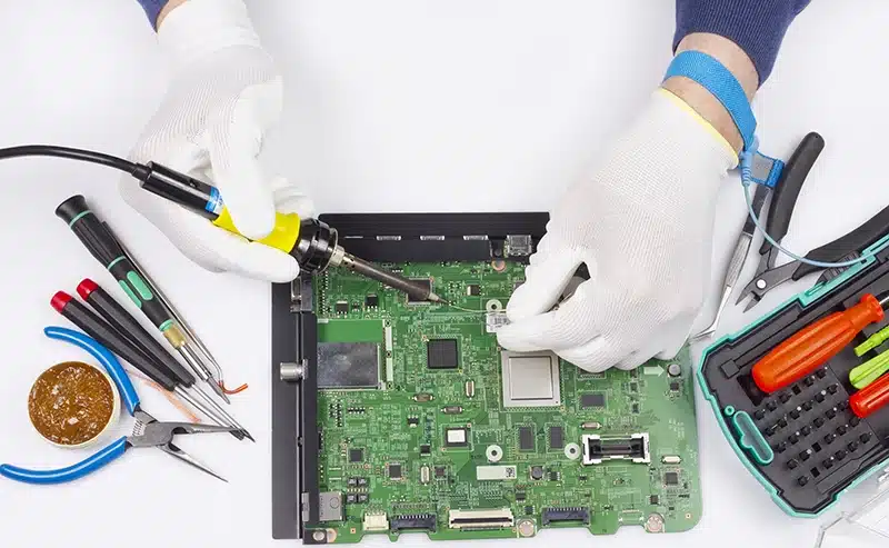 Operator working on PCB board wearing ESD gloves and wrist strap for ESD control