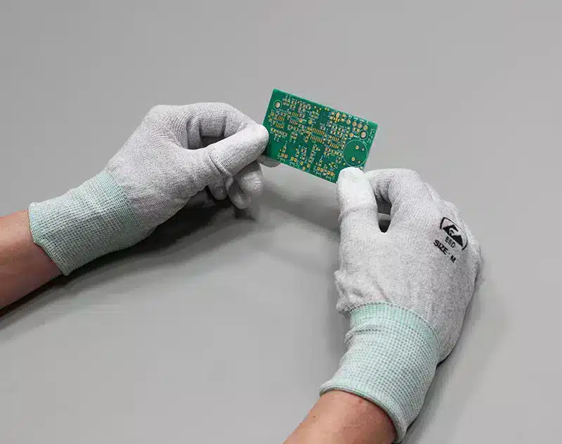 Operator wearing antistatic gloves holding a printed circuit board in both hands. Bondline Electronics Limited.
